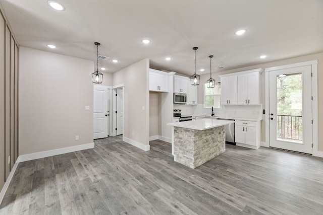 182 Kaanapali Ln, Bastrop, TX 78602 - kitchen featuring appliances with stainless steel finishes, light countertops, white cabinetry, light wood-style flooring, and recessed lighting