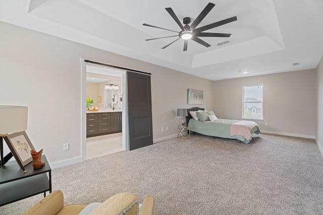 100 Toltec Cv, Kyle, TX 78640 - bedroom featuring a raised ceiling, light carpet, baseboards, and ensuite bathroom
