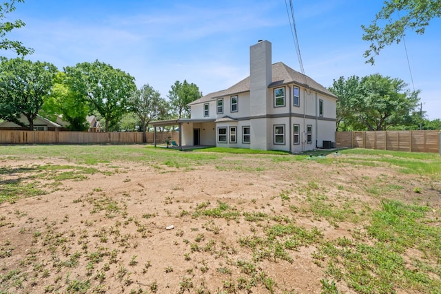 100 Toltec Cv, Kyle, TX 78640 - back of property with a chimney, stucco siding, a fenced backyard, and central AC