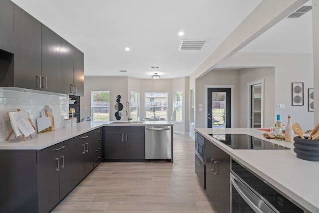 100 Toltec Cv, Kyle, TX 78640 - kitchen featuring appliances with stainless steel finishes, light countertops, a sink, a peninsula, and recessed lighting