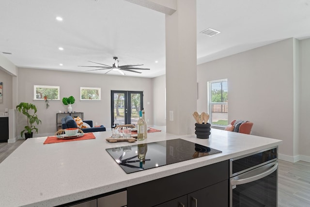 100 Toltec Cv, Kyle, TX 78640 - kitchen with stainless steel oven, light wood-style flooring, black electric cooktop, open floor plan, and recessed lighting