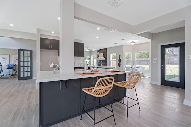 100 Toltec Cv, Kyle, TX 78640 - kitchen with light countertops, light wood-style floors, recessed lighting, a breakfast bar, and a large island