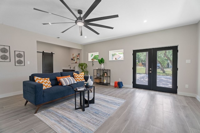 100 Toltec Cv, Kyle, TX 78640 - living room with a barn door, french doors, a ceiling fan, light wood-type flooring, and baseboards