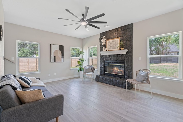 100 Toltec Cv, Kyle, TX 78640 - living area with ceiling fan, a stone fireplace, wood finished floors, and plenty of natural light