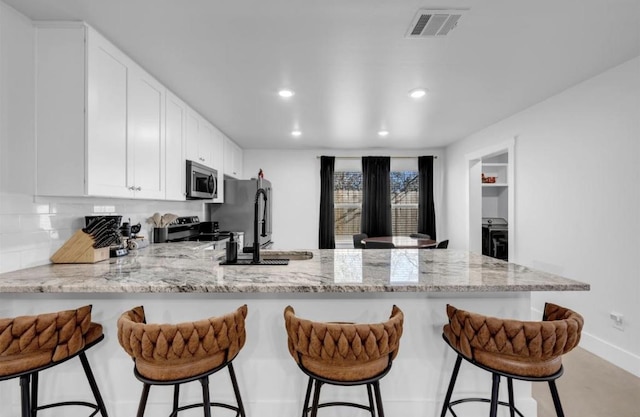249 Hill Dr, Granite Shoals, TX 78654 - kitchen with a peninsula, stainless steel appliances, recessed lighting, a sink, and light stone countertops