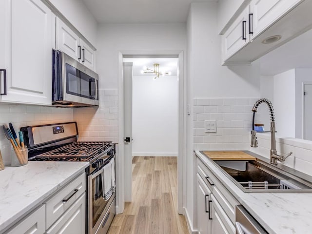 7920 Rockwood Ln Unit 208, Austin, TX 78757 - kitchen featuring appliances with stainless steel finishes, a sink, light wood finished floors, white cabinets, and tasteful backsplash