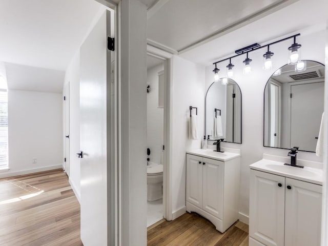 7920 Rockwood Ln Unit 208, Austin, TX 78757 - bathroom with two vanities, wood finished floors, toilet, and baseboards
