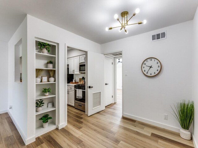 7920 Rockwood Ln Unit 208, Austin, TX 78757 - hallway featuring a chandelier, light wood-style flooring, and baseboards