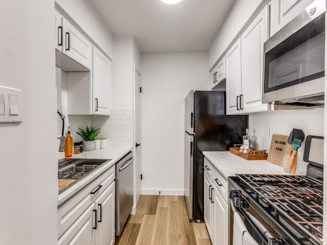 7920 Rockwood Ln Unit 208, Austin, TX 78757 - kitchen featuring stainless steel appliances, light wood-style floors, white cabinets, and tasteful backsplash