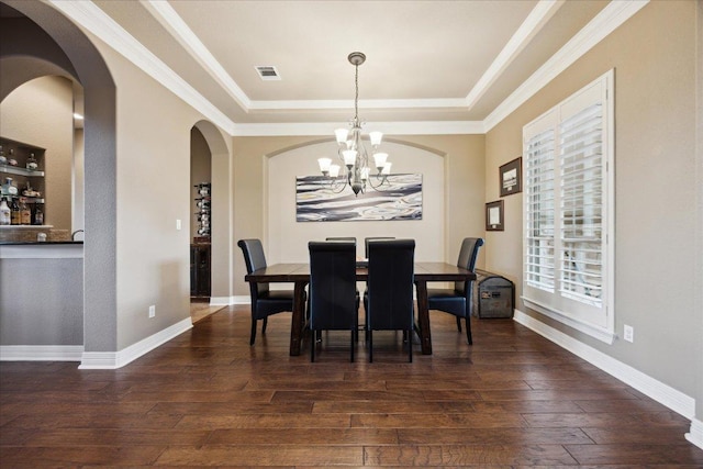 613 Horseback Holw, Austin, TX 78732 - dining area featuring a chandelier, dark wood finished floors, arched walkways, a raised ceiling, and ornamental molding