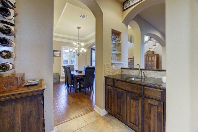 613 Horseback Holw, Austin, TX 78732 - bar area featuring a sink, a chandelier, backsplash, arched walkways, and ornamental molding