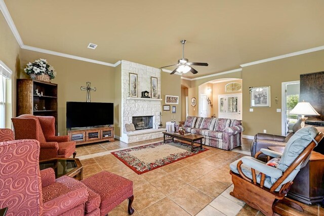 217 Circle Oaks Dr, Burnet, TX 78611 - living area with light tile patterned floors, crown molding, arched walkways, a stone fireplace, and ceiling fan