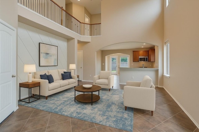 9837 Milla Cir Unit 72, Austin, TX 78748 - living area with a towering ceiling, dark tile patterned flooring, arched walkways, and baseboards