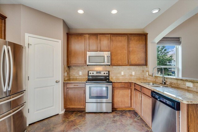 9837 Milla Cir Unit 72, Austin, TX 78748 - kitchen with stainless steel appliances, a sink, brown cabinetry, light stone counters, and recessed lighting