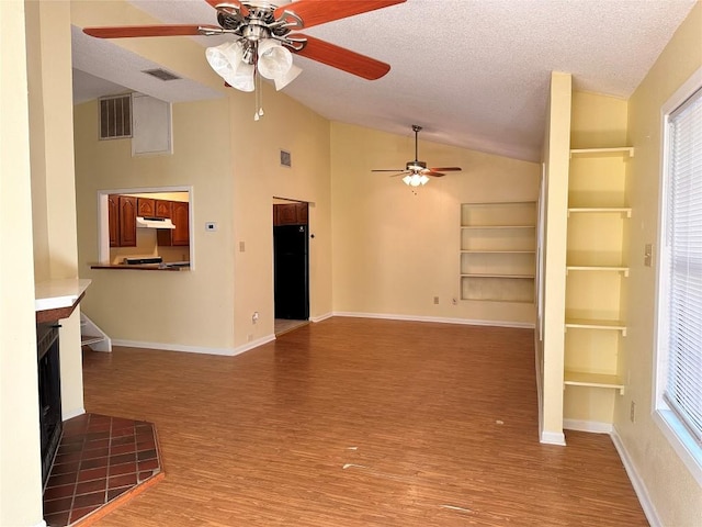 899 Hillyer St Unit 901, San Marcos, TX 78666 - unfurnished living room with ceiling fan, vaulted ceiling, wood finished floors, a textured ceiling, and built in features