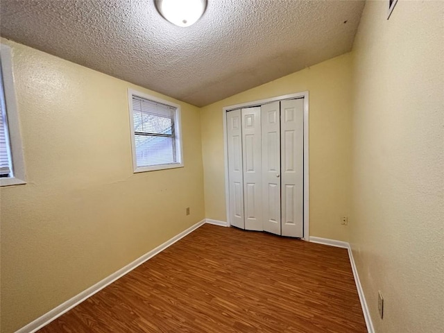 899 Hillyer St Unit 901, San Marcos, TX 78666 - unfurnished bedroom with dark wood finished floors, lofted ceiling, a textured ceiling, baseboards, and a closet