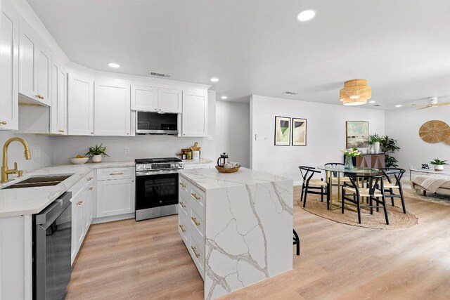 7302 Hartnell Dr, Austin, TX 78723 - kitchen featuring stainless steel appliances, a sink, recessed lighting, light wood-type flooring, and white cabinetry