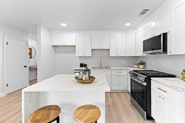7302 Hartnell Dr, Austin, TX 78723 - kitchen featuring stainless steel appliances, a sink, light wood-style flooring, white cabinets, and recessed lighting
