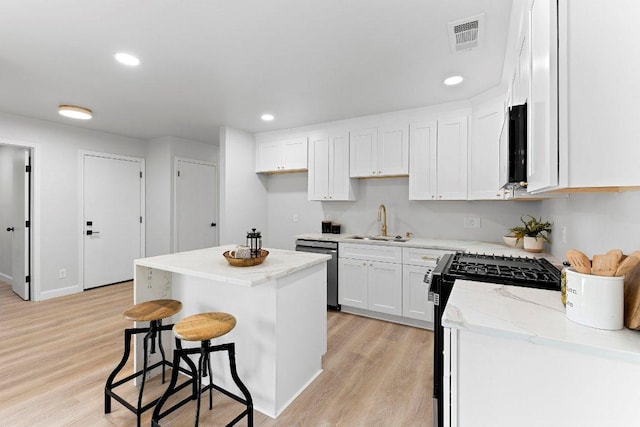 7302 Hartnell Dr, Austin, TX 78723 - kitchen with dishwasher, a sink, white cabinets, light wood-style floors, and range with gas stovetop