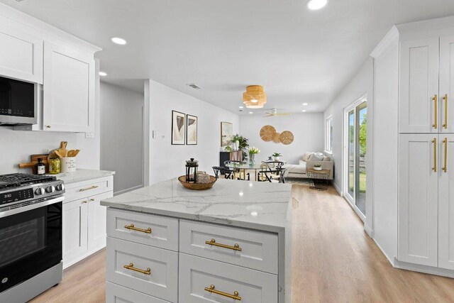 7302 Hartnell Dr, Austin, TX 78723 - kitchen with stainless steel appliances, light wood-style floors, a kitchen island, open floor plan, and white cabinets