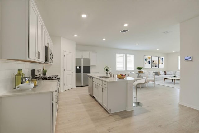 465 Brooks Ranch Dr, Kyle, TX 78640 - kitchen with stainless steel appliances, light wood-type flooring, white cabinetry, light countertops, and a kitchen island with sink