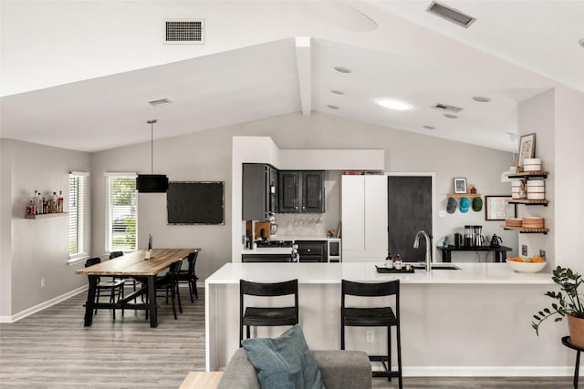 8504 Verona Trl, Austin, TX 78749 - kitchen with light wood-style flooring, light countertops, a peninsula, hanging light fixtures, and a breakfast bar