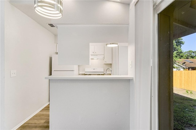 9406 Quail Meadow Dr, Austin, TX 78758 - kitchen with fridge, stove, under cabinet range hood, white cabinetry, and light countertops