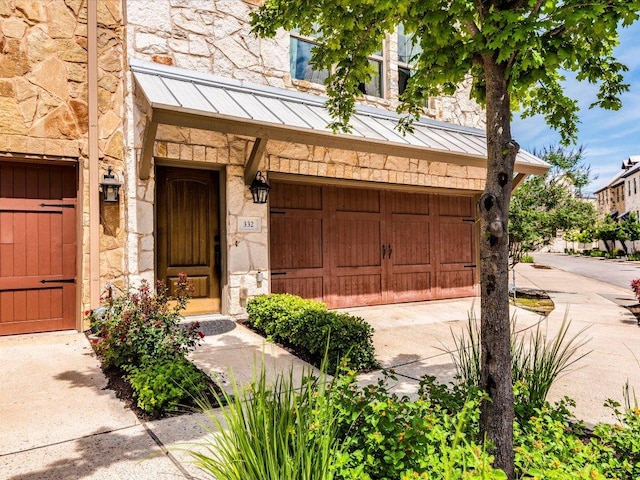 332 Adams St, Georgetown, TX 78628 - view of exterior entry with a standing seam roof, stone siding, an attached garage, driveway, and metal roof