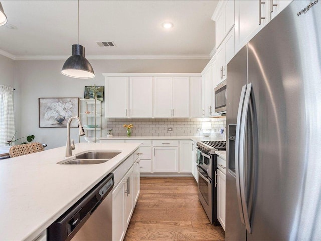 332 Adams St, Georgetown, TX 78628 - kitchen featuring stainless steel appliances, a sink, ornamental molding, light countertops, and white cabinets