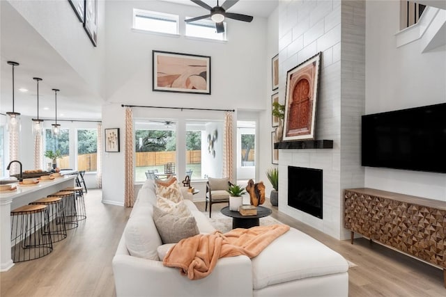 1403 Plum Tree Way, Georgetown, TX 78628 - living room with ceiling fan, light wood-style flooring, a high ceiling, a fireplace, and baseboards