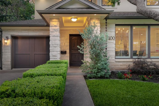 2400 Pruett St, Austin, TX 78703 - property entrance with stone siding, an attached garage, a shingled roof, and asphalt driveway