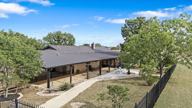 204 Bridges Ln, Buda, TX 78610 - back of house with a patio area, metal roof, a fenced backyard, and a standing seam roof