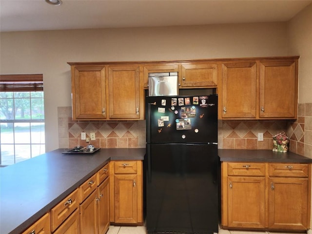 1726 Riverchase Ave, Smithville, TX 78957 - kitchen featuring freestanding refrigerator, tasteful backsplash, dark countertops, and brown cabinets