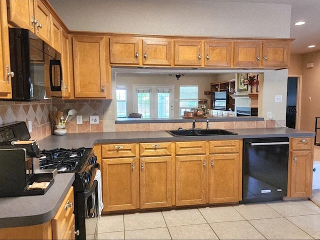 1726 Riverchase Ave, Smithville, TX 78957 - kitchen with black appliances, a sink, brown cabinetry, light tile patterned floors, and a peninsula