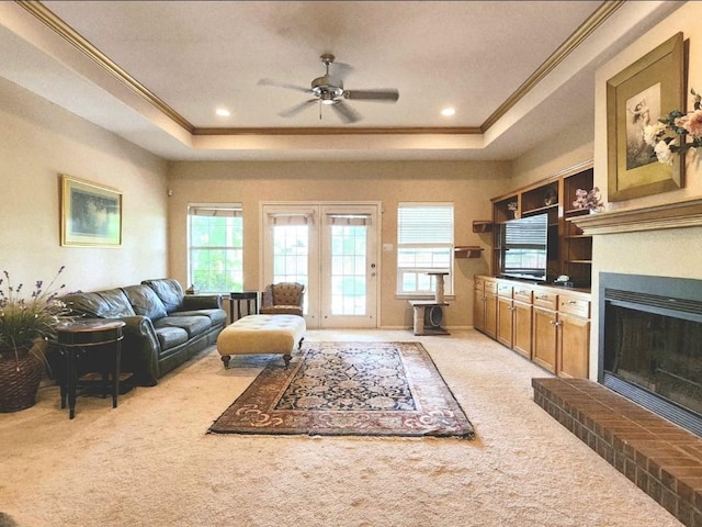 1726 Riverchase Ave, Smithville, TX 78957 - living area with a tray ceiling, crown molding, light carpet, ceiling fan, and a fireplace with raised hearth
