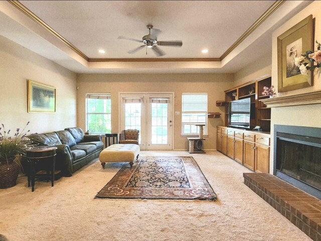 1726 Riverchase Ave, Smithville, TX 78957 - living room with a raised ceiling, crown molding, light carpet, ceiling fan, and a fireplace with raised hearth
