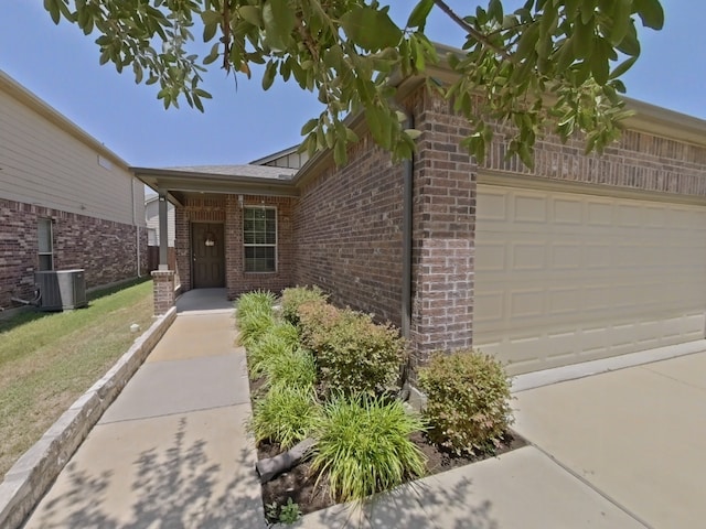 10116 Aly May Dr, Austin, TX 78748 - view of exterior entry featuring central AC, brick siding, an attached garage, and a lawn