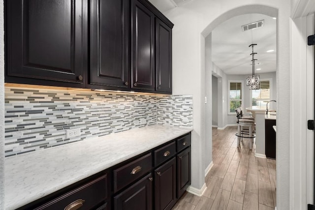 5109 Scenic Lake Dr, Georgetown, TX 78626 - kitchen featuring arched walkways, baseboards, light countertops, tasteful backsplash, and light wood-style flooring