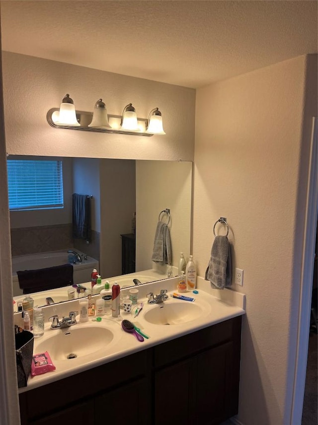 bathroom featuring double vanity, a bath, a textured ceiling, and a textured wall