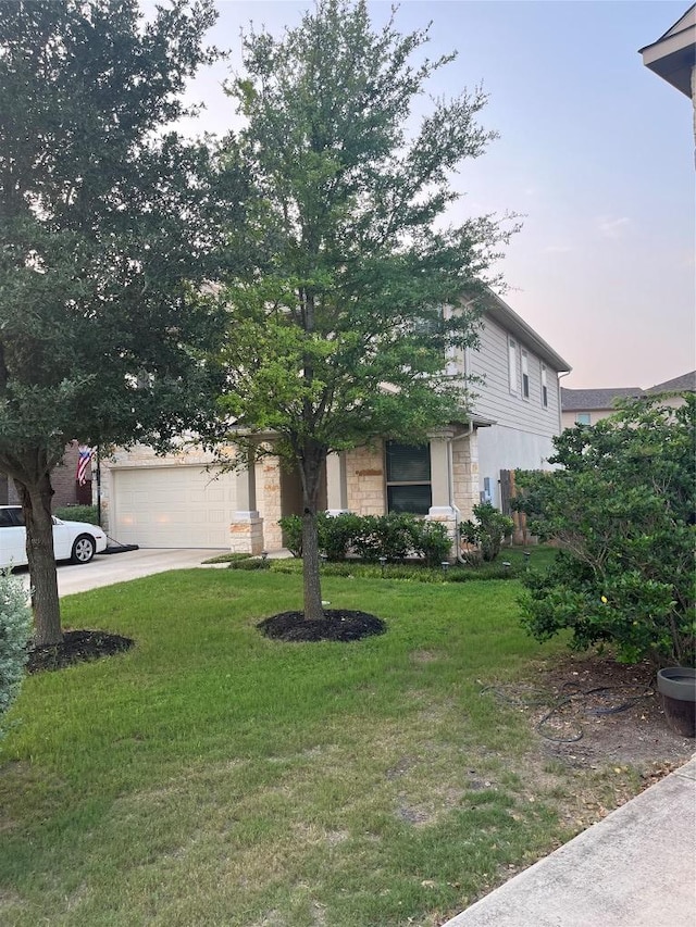 view of property hidden behind natural elements featuring a front lawn, concrete driveway, and a garage