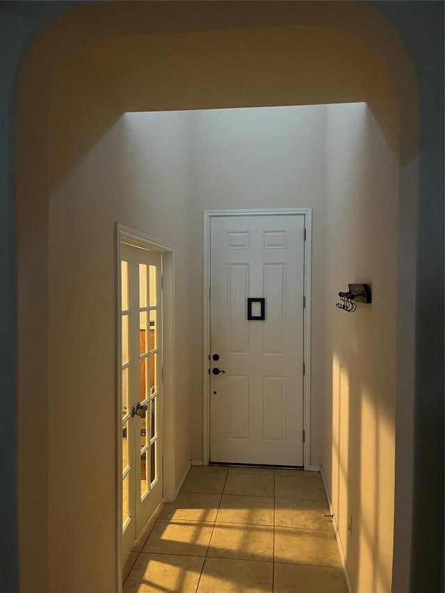 doorway with french doors, light tile patterned flooring, and baseboards