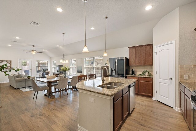 3633 Mineral Dr, Leander, TX 78641 - kitchen with appliances with stainless steel finishes, a sink, vaulted ceiling, tasteful backsplash, and light wood finished floors