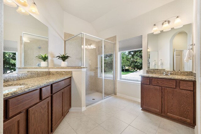 3633 Mineral Dr, Leander, TX 78641 - bathroom featuring healthy amount of natural light, a shower stall, two vanities, tile patterned flooring, and vaulted ceiling