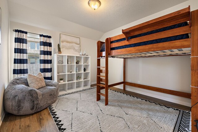 3633 Mineral Dr, Leander, TX 78641 - bedroom featuring wood finished floors, vaulted ceiling, and baseboards
