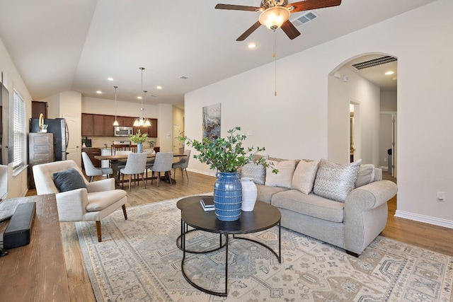 3633 Mineral Dr, Leander, TX 78641 - living area with light wood-type flooring, ceiling fan, vaulted ceiling, arched walkways, and baseboards