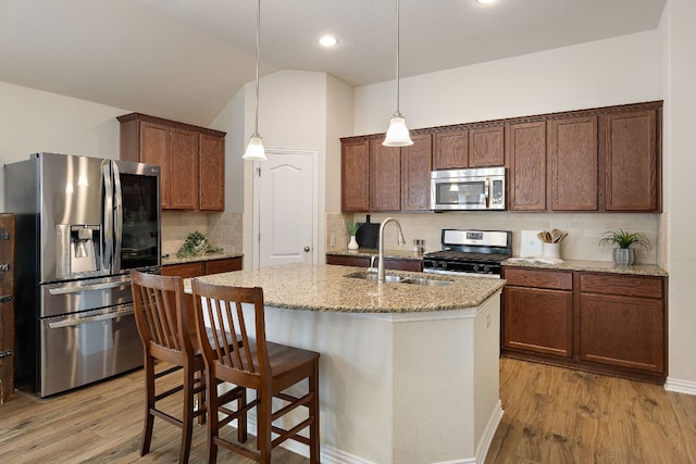 3633 Mineral Dr, Leander, TX 78641 - kitchen featuring stainless steel appliances, a sink, light wood-style flooring, decorative backsplash, and an island with sink