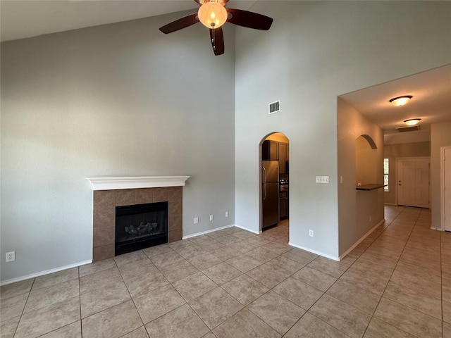 2009 Meadow View Dr, San Marcos, TX 78666 - unfurnished living room with ceiling fan, arched walkways, a high ceiling, light tile patterned floors, and baseboards