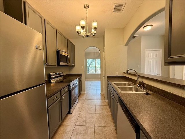 2009 Meadow View Dr, San Marcos, TX 78666 - kitchen featuring stainless steel appliances, arched walkways, a sink, dark countertops, and light tile patterned flooring