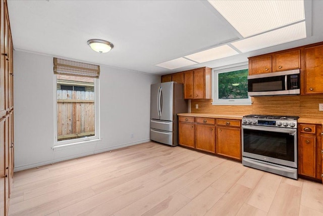 4831 Trail Crest Cir, Austin, TX 78735 - kitchen with appliances with stainless steel finishes, brown cabinets, light countertops, light wood-type flooring, and backsplash