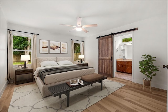 4831 Trail Crest Cir, Austin, TX 78735 - bedroom with a barn door, multiple windows, light wood finished floors, and baseboards